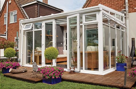 A white conservatory sitting on a wooden deck.