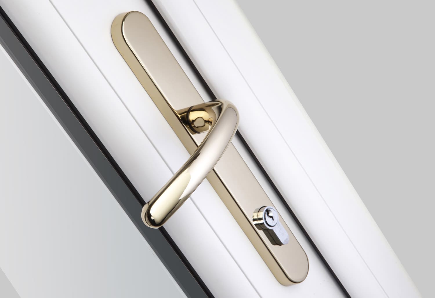 A close up of a white window handle with a gold handle.